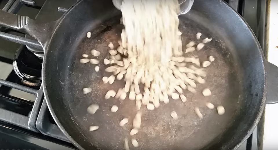 Green coffee beans being poured into a pan