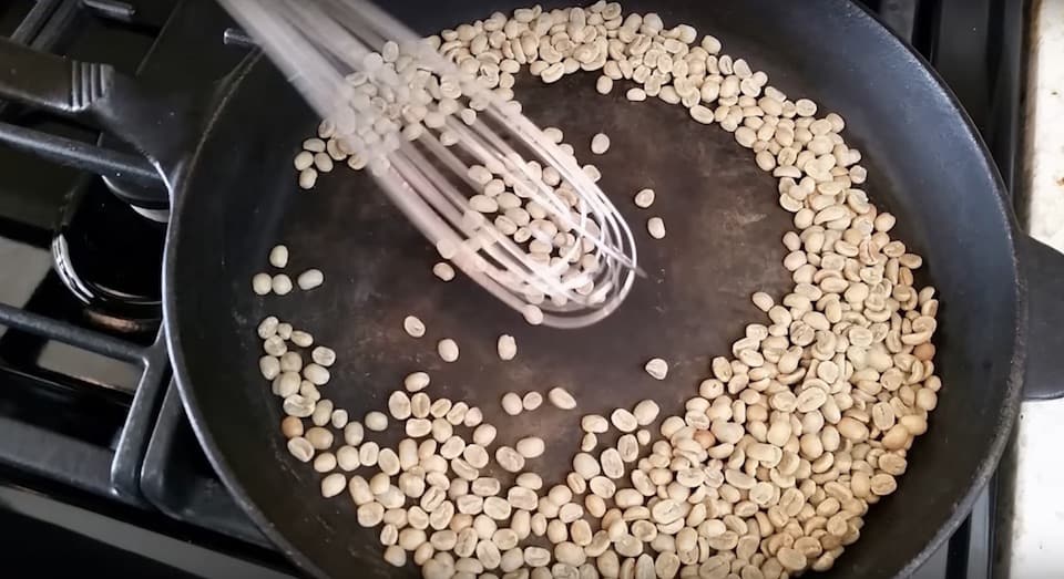 Stirring coffee beans with a whisk