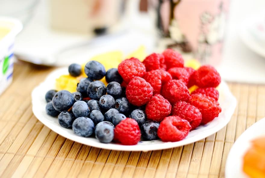 Plate of blueberries and raspberries on a picnic table