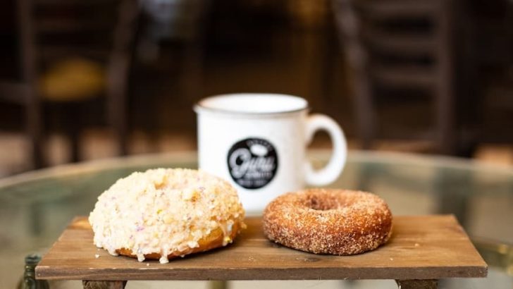two donuts on a board in front of a cup of coffee