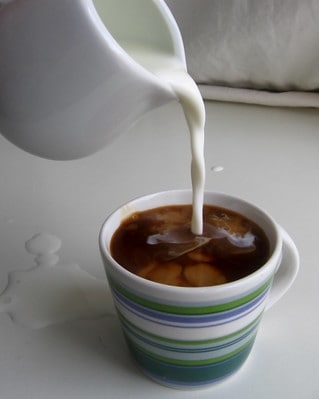 Pouring milk into a cup of coffee