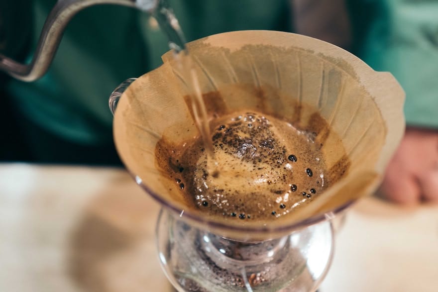 Closeup of water being poured onto the grounds in a Hario V60 coffee brewer
