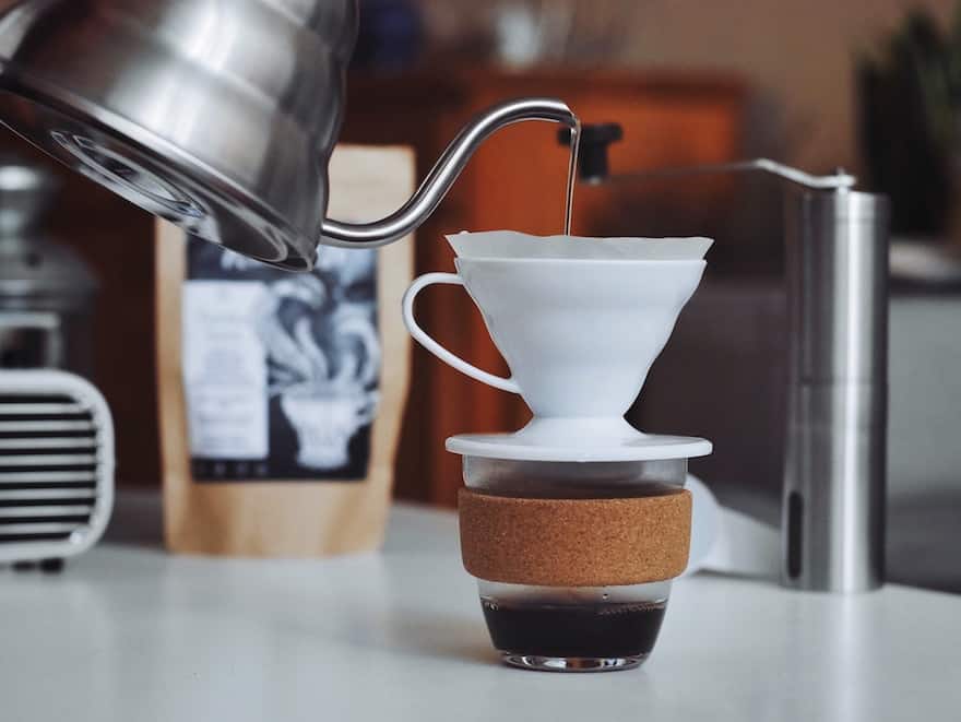 Hario gooeseneck kettle pouring into a ceramic Hario V60 coffee brewer