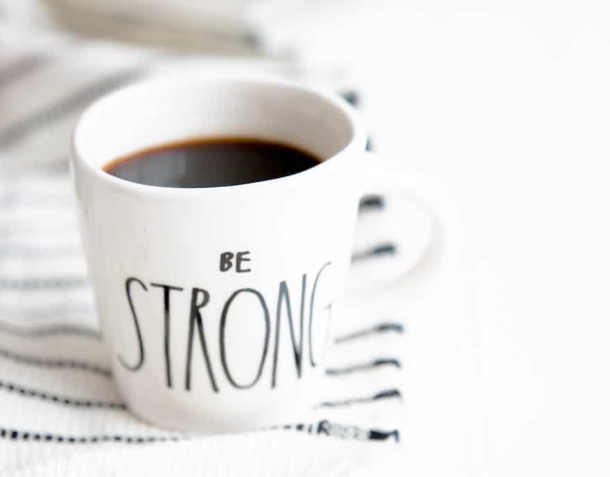 A white coffee mug with the words Be Strong written on the outside