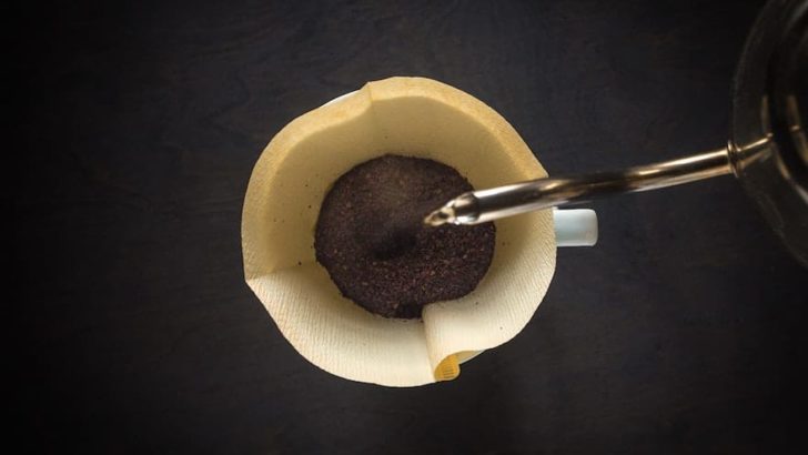Kettle pouring water into a cone coffee filter from above