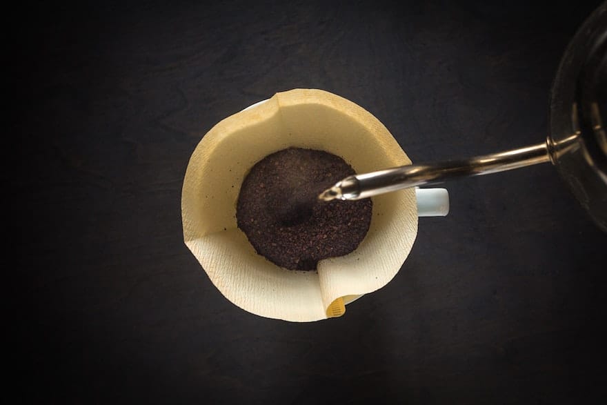 Kettle pouring water into a cone coffee filter from above