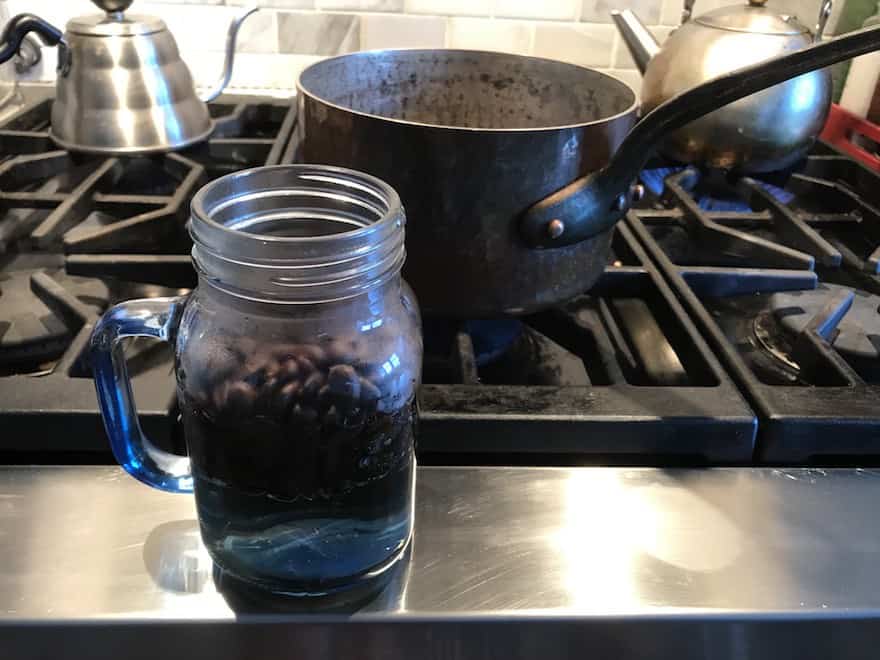 Coffee beans in a mason jar with hot water added