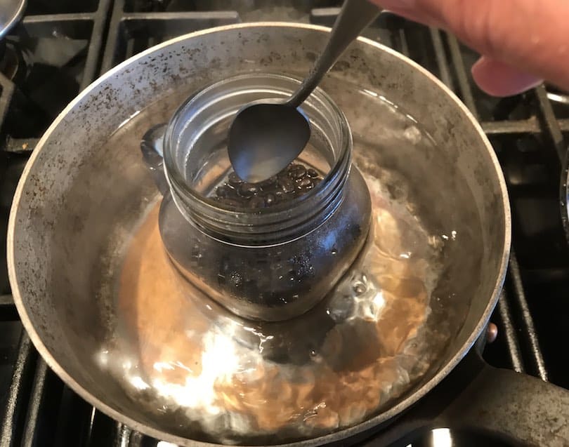 Stirring coffee beans in mason jar