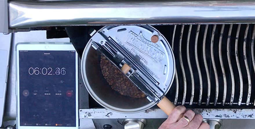 Overhead shot of coffee roasting in a Whirley Pop with an iPad keeping time next to it