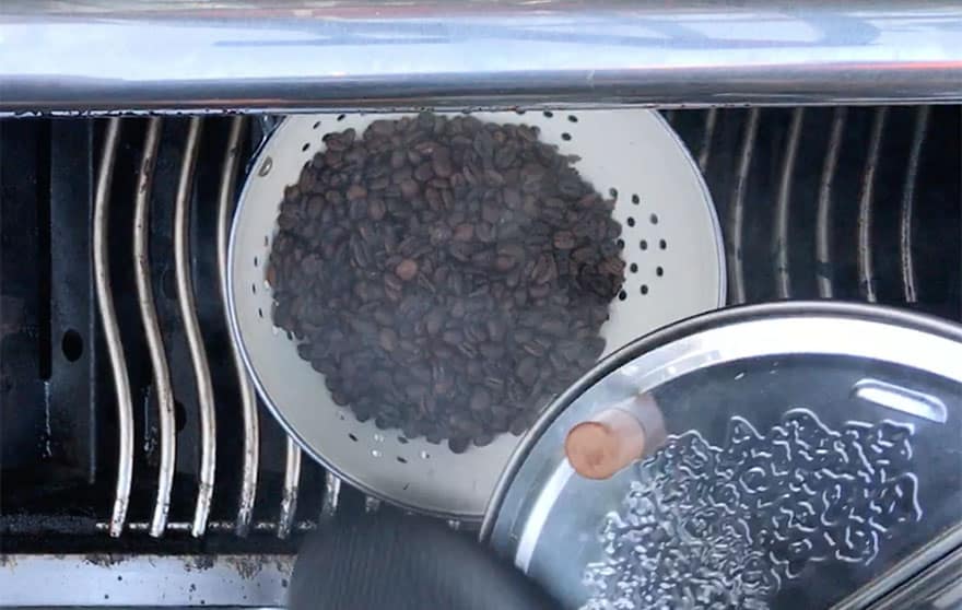 Dumping hot roasted coffee beans into a colander to cool
