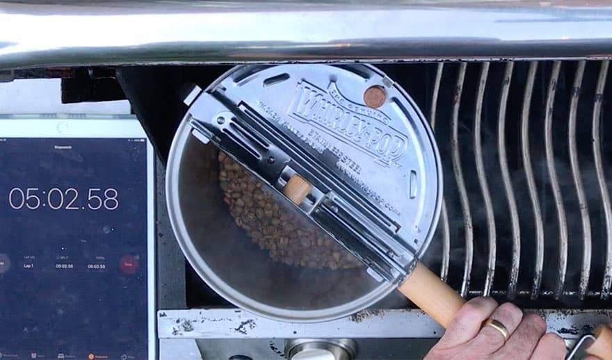 Peeking into the lid of a Whirley Pop while coffee is roasting on the barbecue