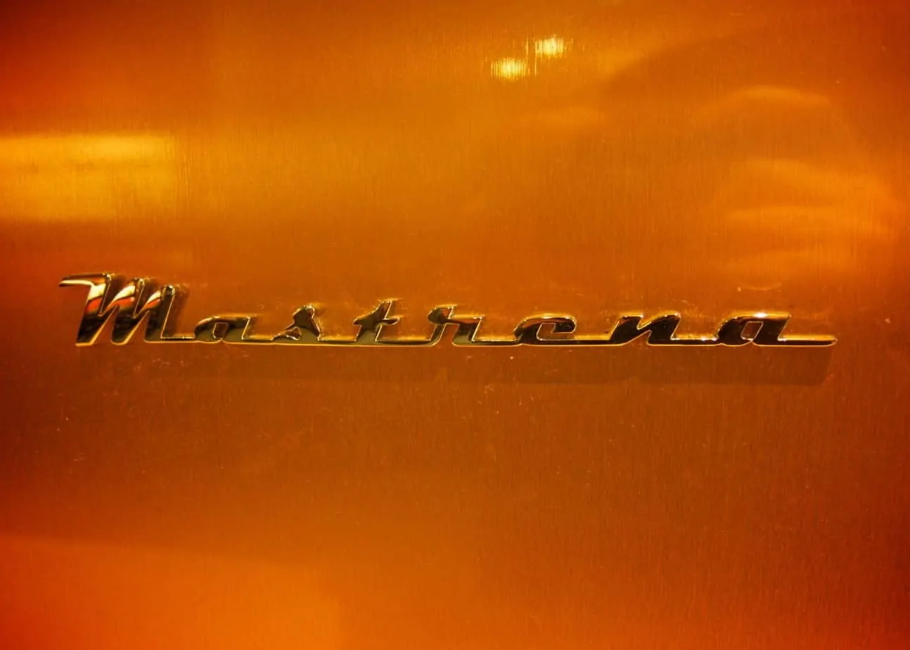 Picture of the mastrena coffee machine logo on a brass background.