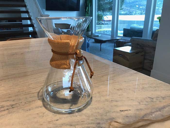 A shiny glass Chemex sitting on a kitchen counter