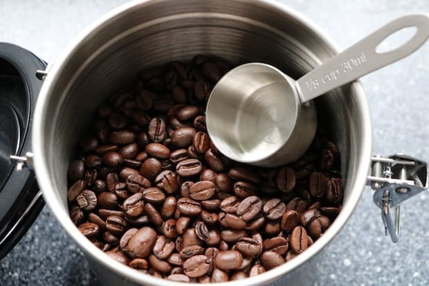 Coffee scoop dipping into a container of coffee beans