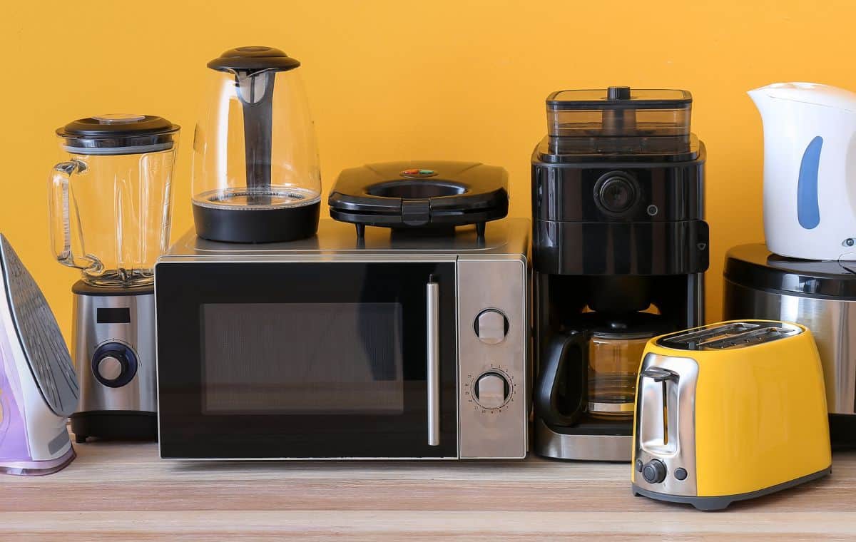 Coffee maker sitting next to a microwave with other appliances on a kitchen counter