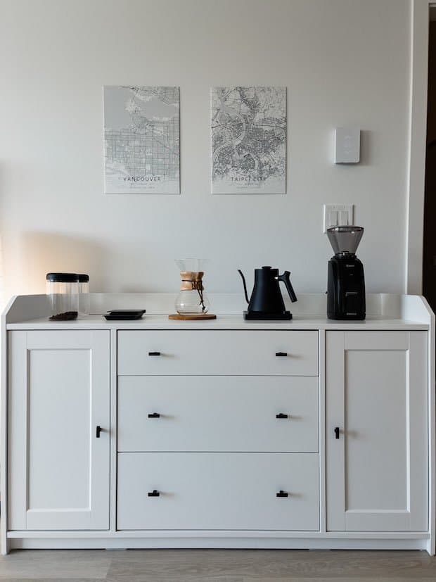 Coffee station in white, set up on a dresser against the wall