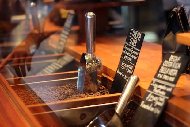 Roasted specialty coffee beans under a glass case at a coffee shop