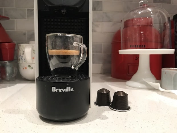 Breville Essenza Plus Nespresso machine on a kitchen counter with a brewed espresso on its platform