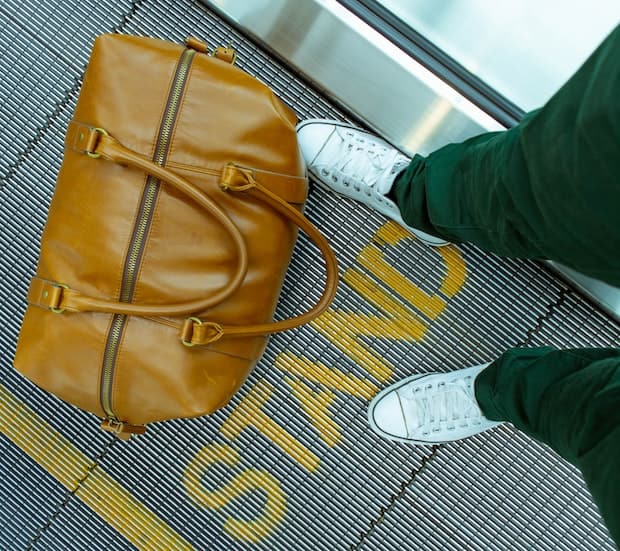 Bag on an airport walkway next to a person's feet