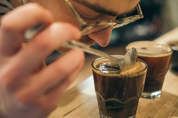 Coffee sommelier, also known as a Q grader, evaluating a small glass of coffee