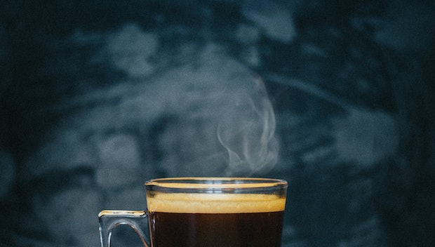 A piping hot cup of Nespresso coffee with steam rising from the top