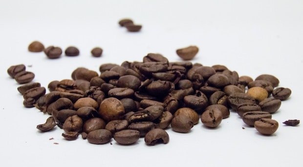 Roasted coffee beans spread across a white surface