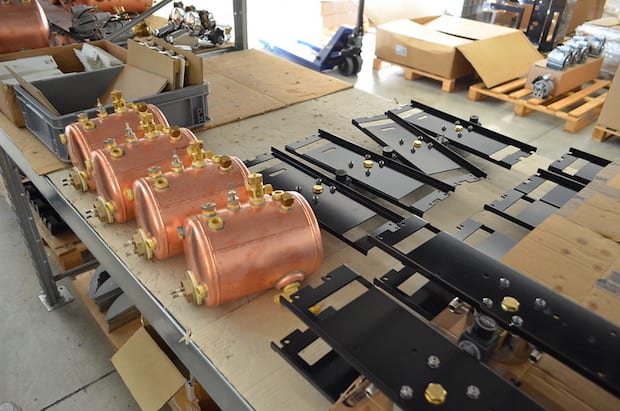 Copper boilers spread out on a table at an espresso machine factory
