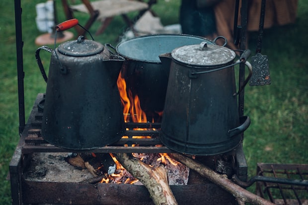 Battered tin coffee pots blackened by carbon over an open fire