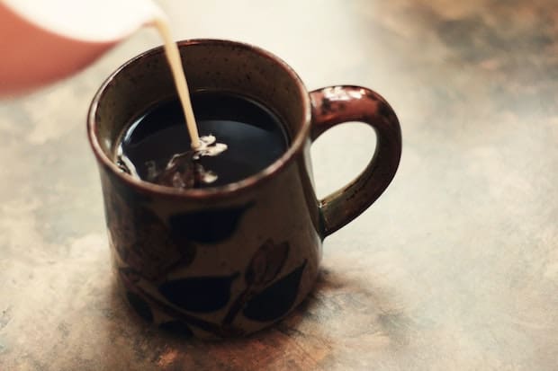 Milk being poured into a cup of coffee