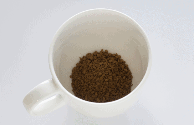 Instant coffee crystals in the bottom of a white mug