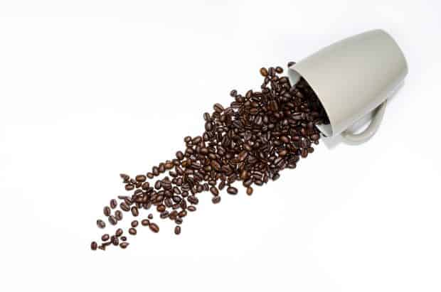 Coffee beans pouring out of cup for use in an espresso machine