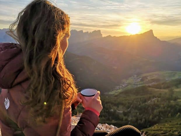 Woman enjoying cup of coffee in the mountains after using high altitude coffee maker