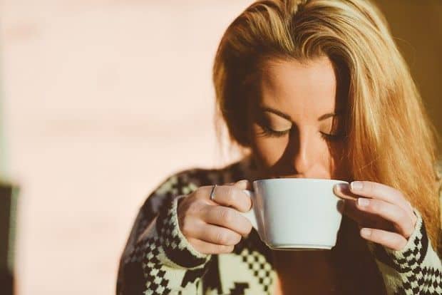 Woman sipping coffee from coffee mug after using Nespresso tips and tricks