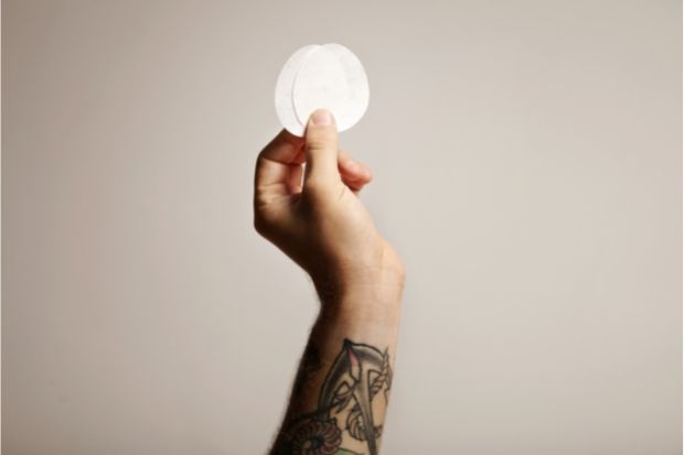 Hand holding up coffee filters for comparison between AeroPress metal filter vs paper