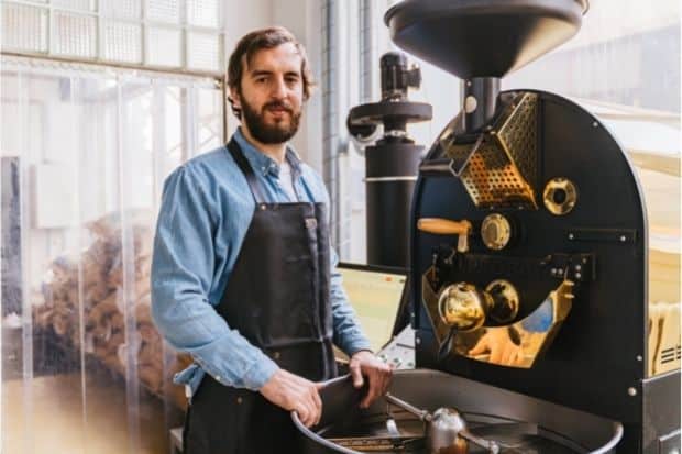 Man standing next to coffee roaster ready to show you how to get into coffee