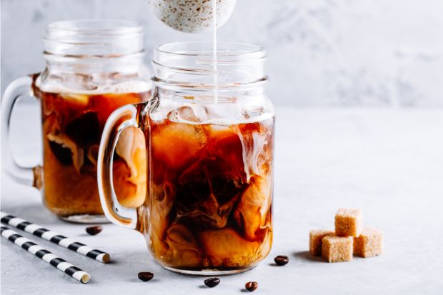 Cream being poured into Thai coffee in mason jar mugs