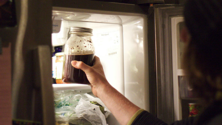Hand pulling cold brew coffee out of the fridge