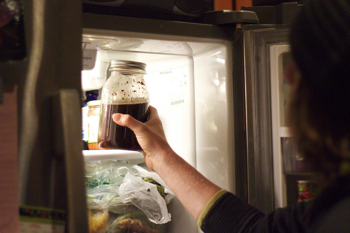 Hand pulling cold brew coffee out of the fridge