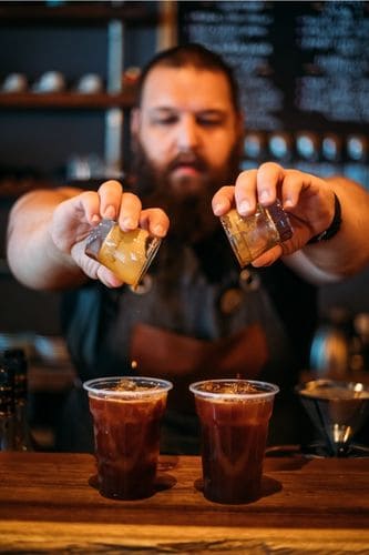 Man making iced Americanos instead of cold brew coffee