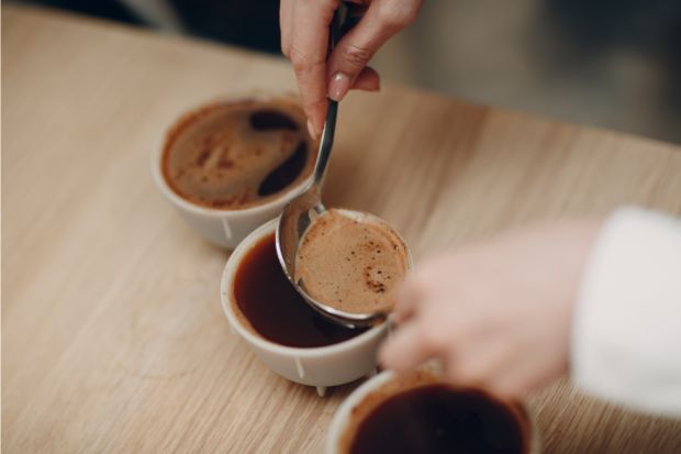 Woman spooning coffee out of cup after learning how to aerate coffee