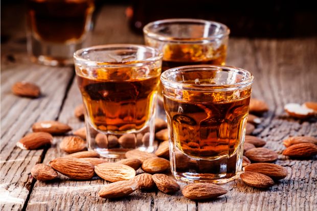 Glasses of amaretto liqueur on a table surrounded by almonds