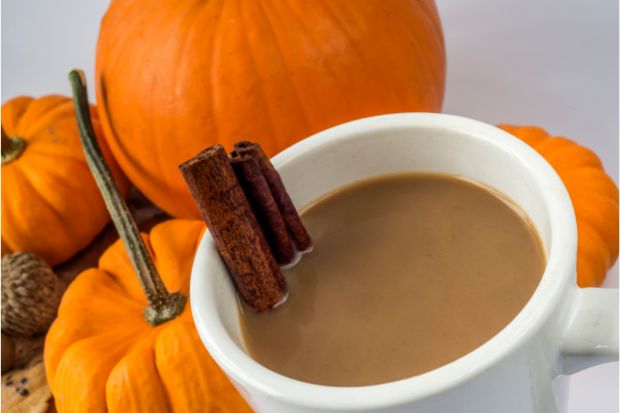 Cinnamon sticks in a cup of coffee that's been flavored with pumpkin spice
