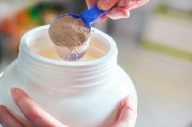 Person scooping out protein powder, which is a great coffee creamer substitute