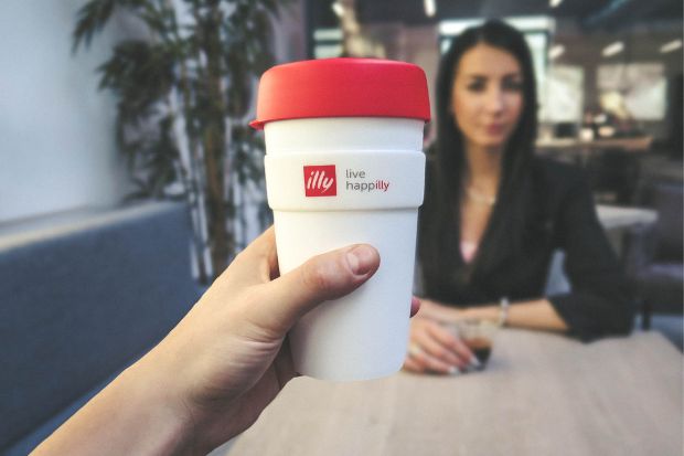 Person holding up Illy coffee cup instead of Lavazza cup