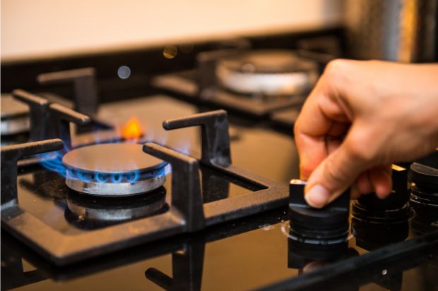 Person turning on stove burner for reheating coffee