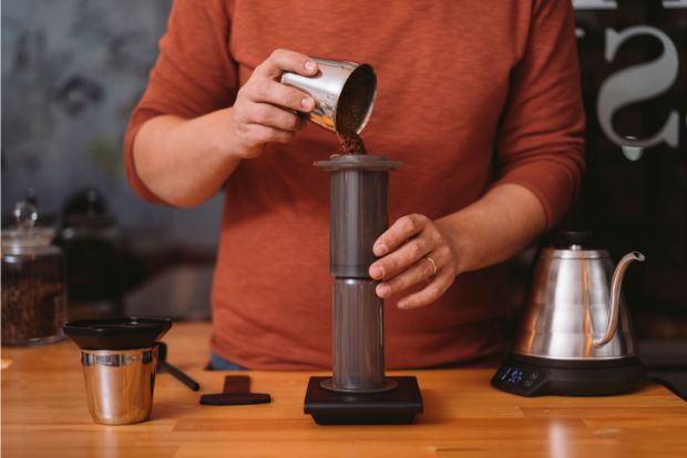 Man filling up AeroPress coffee machine after learning the best method for reheating coffee