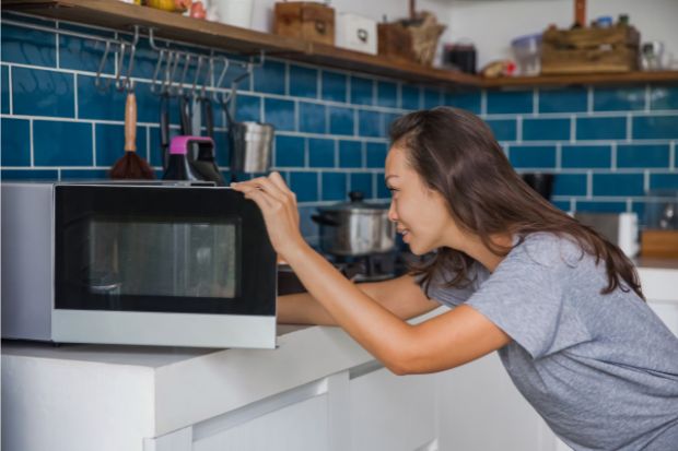 Woman reheating coffee in microwave