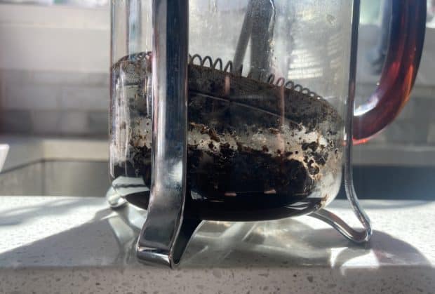Coffee grounds in the bottom of a dirty French press