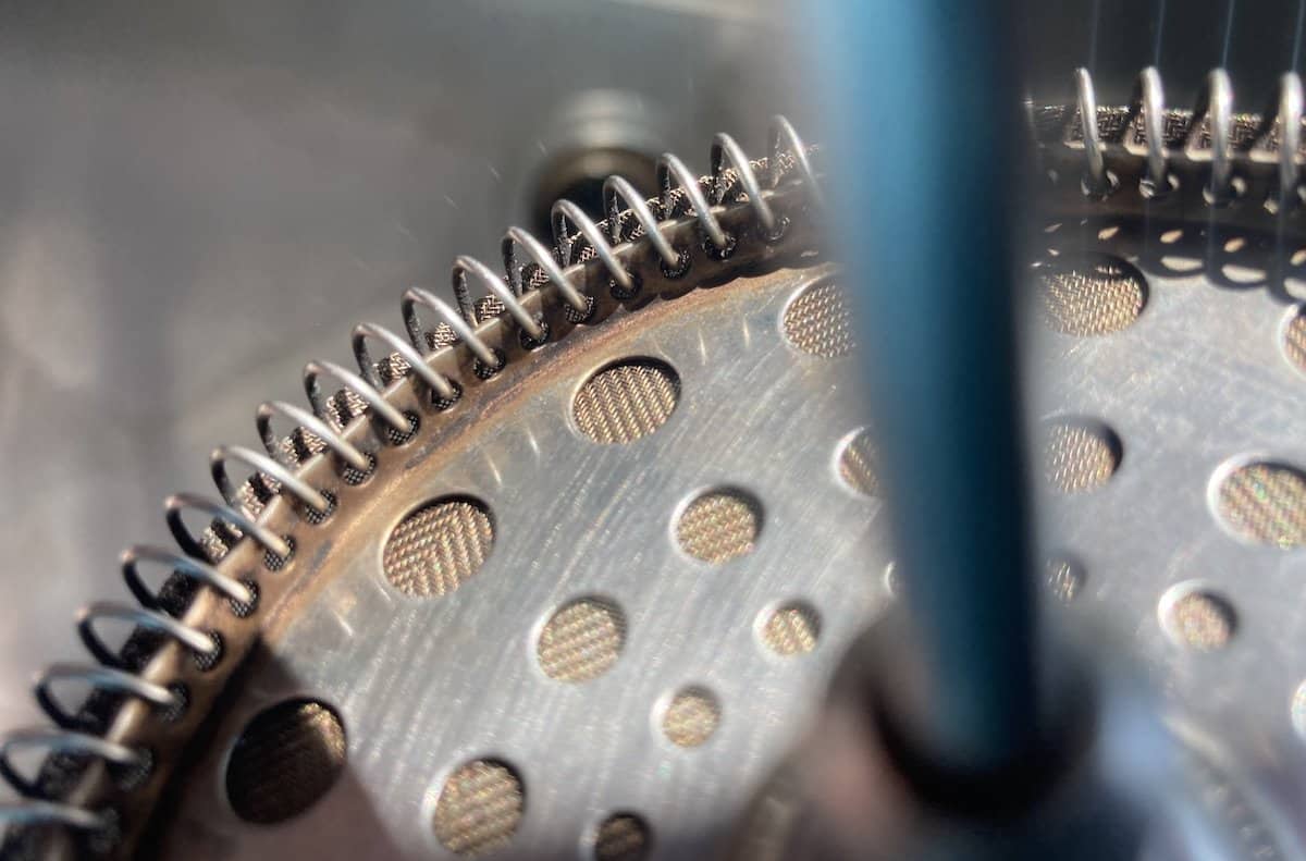 Closeup of brown residue accumulating on the plunger of a French press that hasn't been cleaned well enough