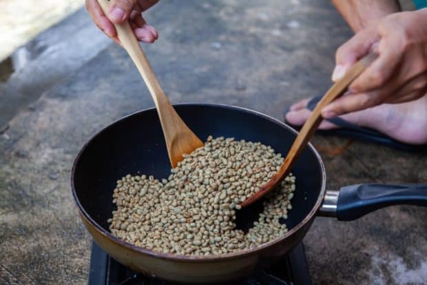 Man roasting green coffee beans in a pan